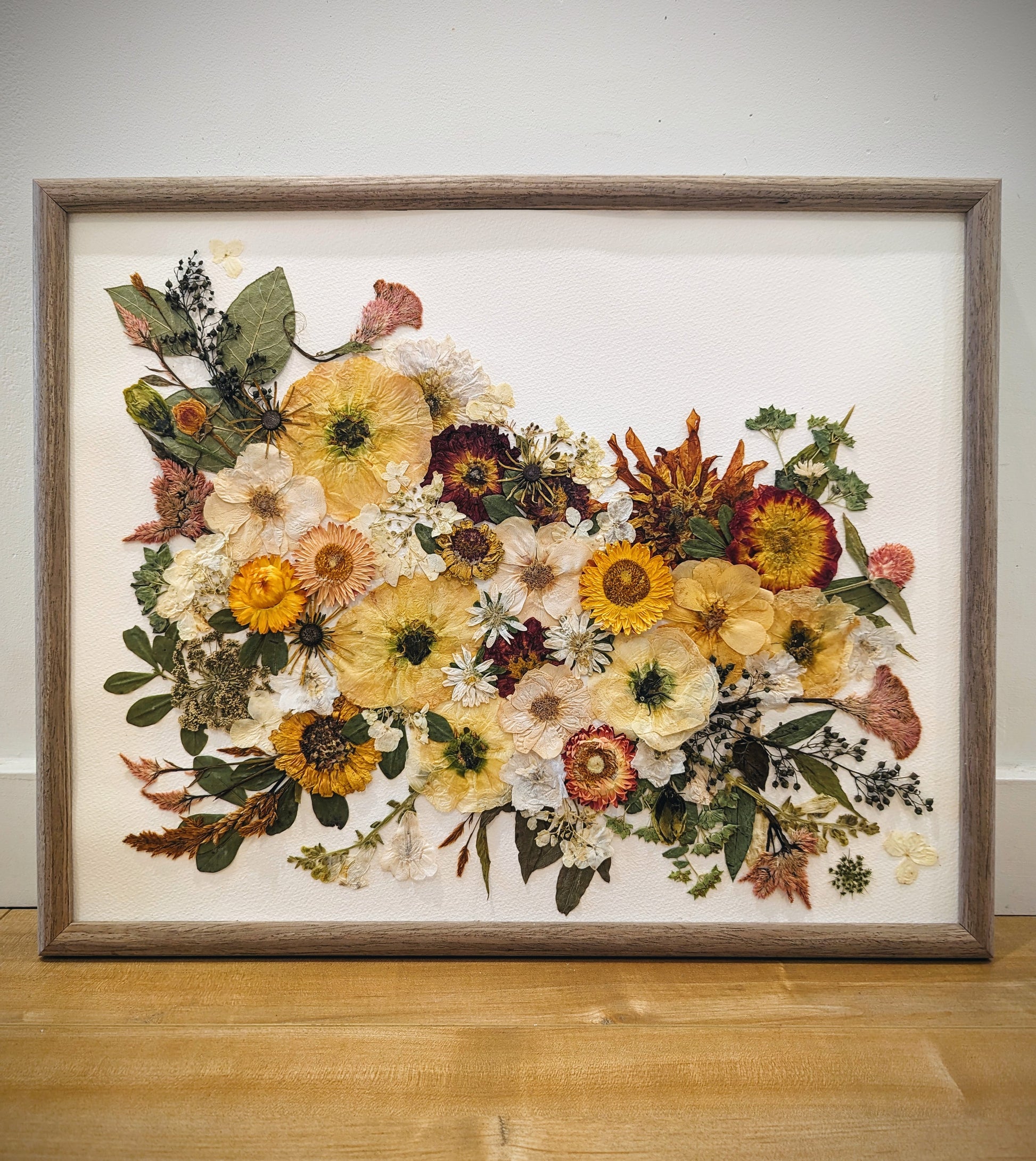 Pressed flower artwork with intricate floral patterns in a wooden frame.