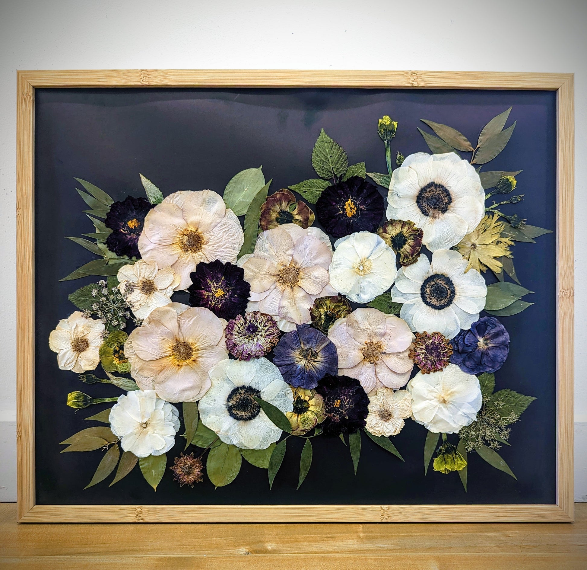 Pressed flower artwork with intricate floral patterns in a wooden frame.