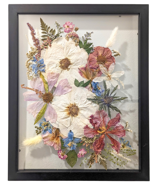 Pressed flower arrangement displayed as a centerpiece in a glass frame.