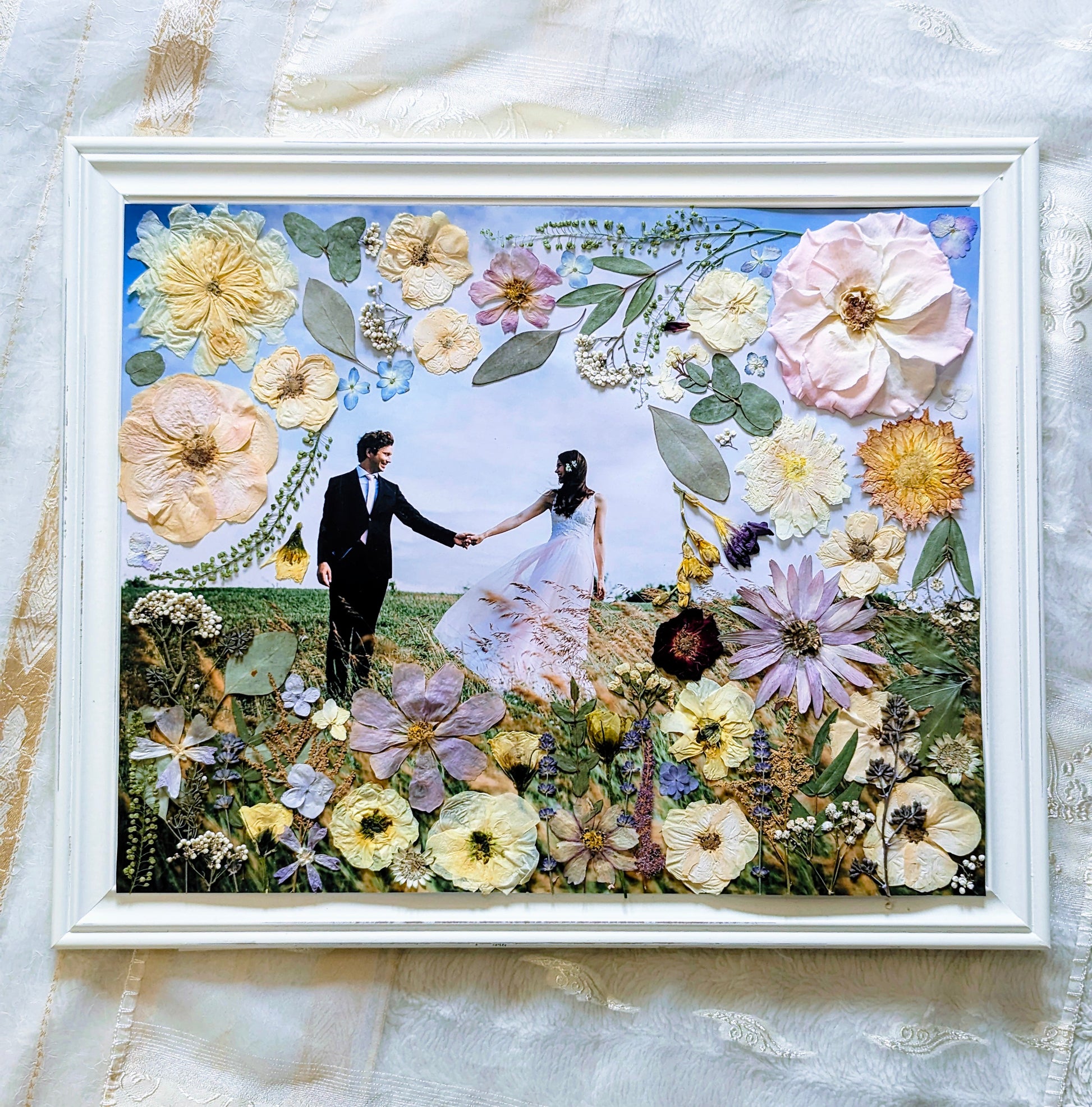 Pressed flower art piece featuring delicate pink roses and green leaves.