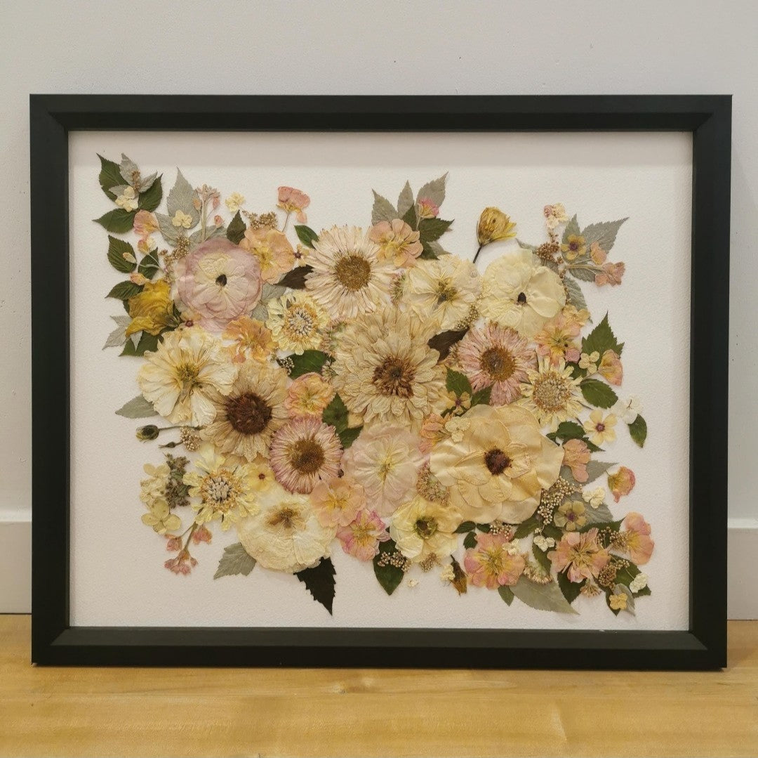 Pressed flower artwork with intricate floral patterns in a wooden frame.