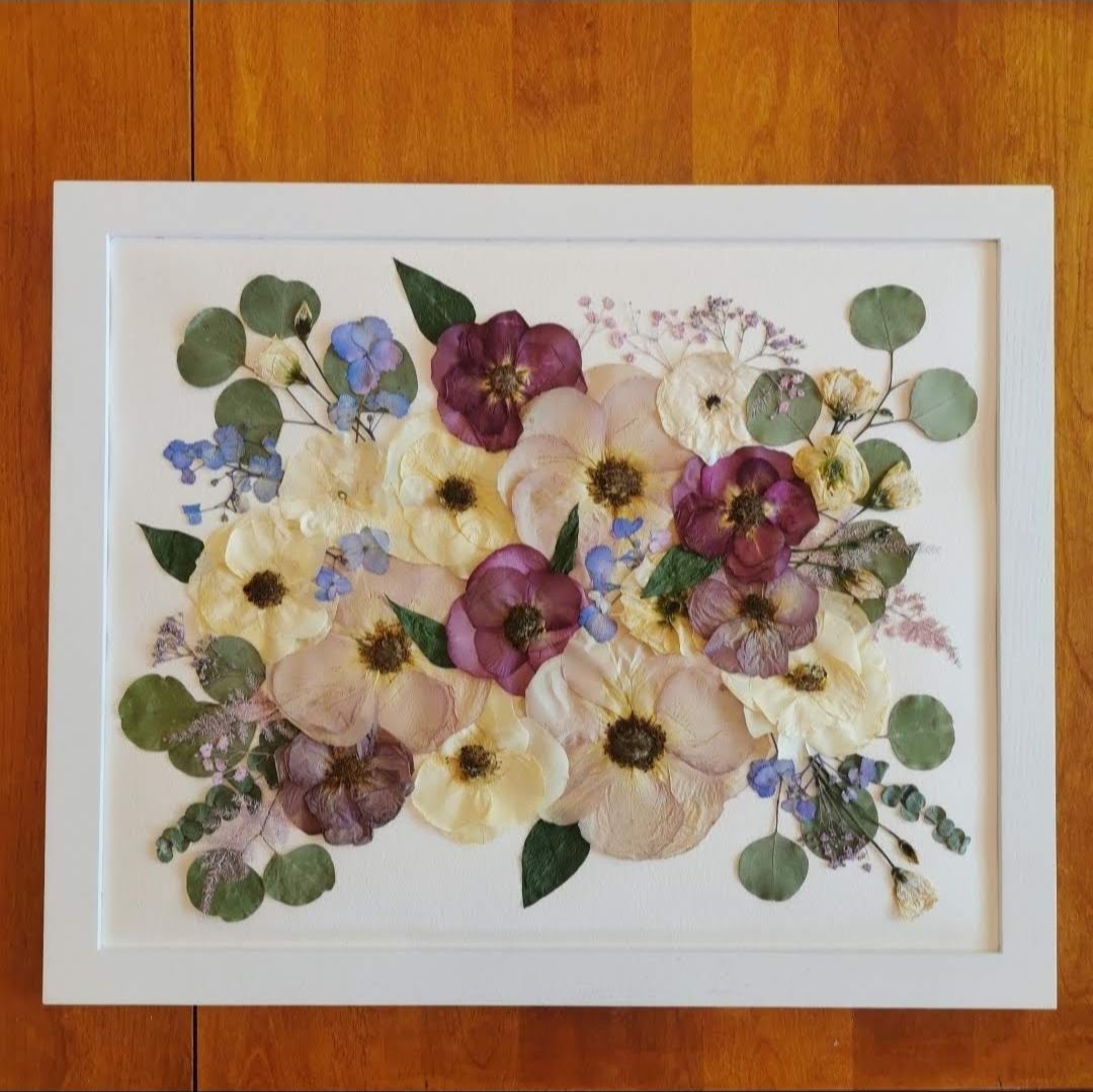 Detailed view of a pressed flower bouquet preserved in a shadow box frame.