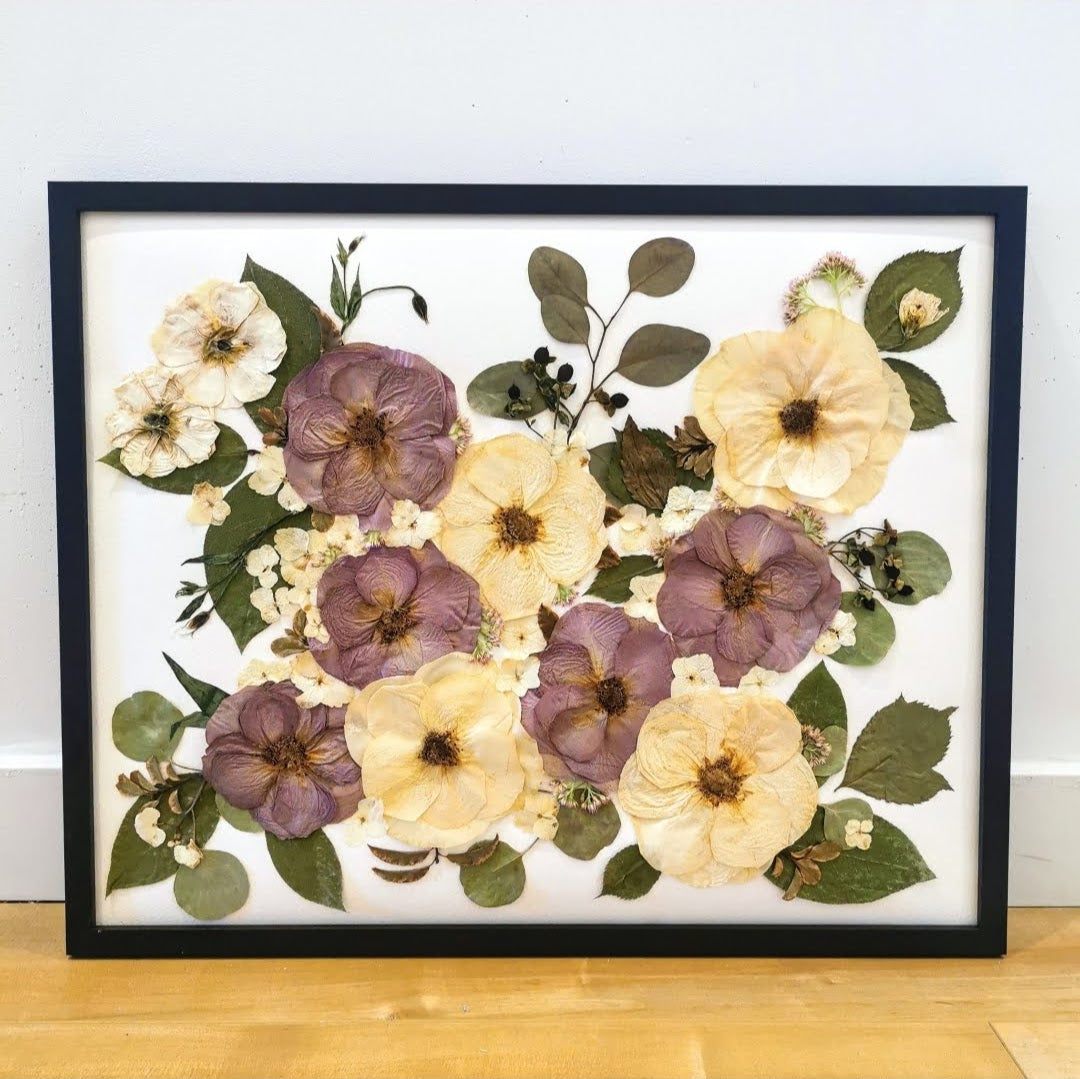 Detailed view of a pressed flower bouquet preserved in a shadow box frame.